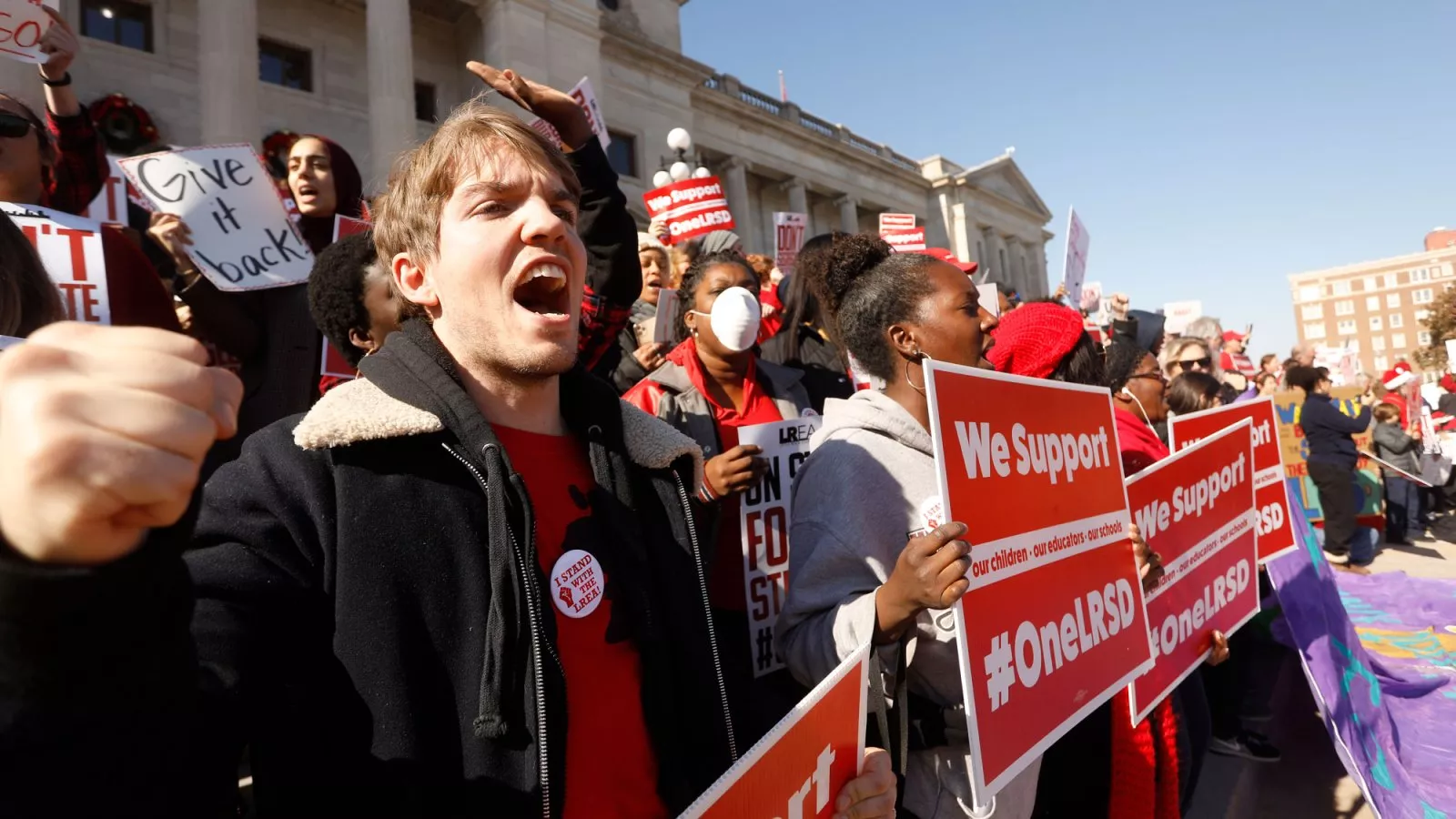 Educators holding signs and wearing red rally in Little Rock, AR