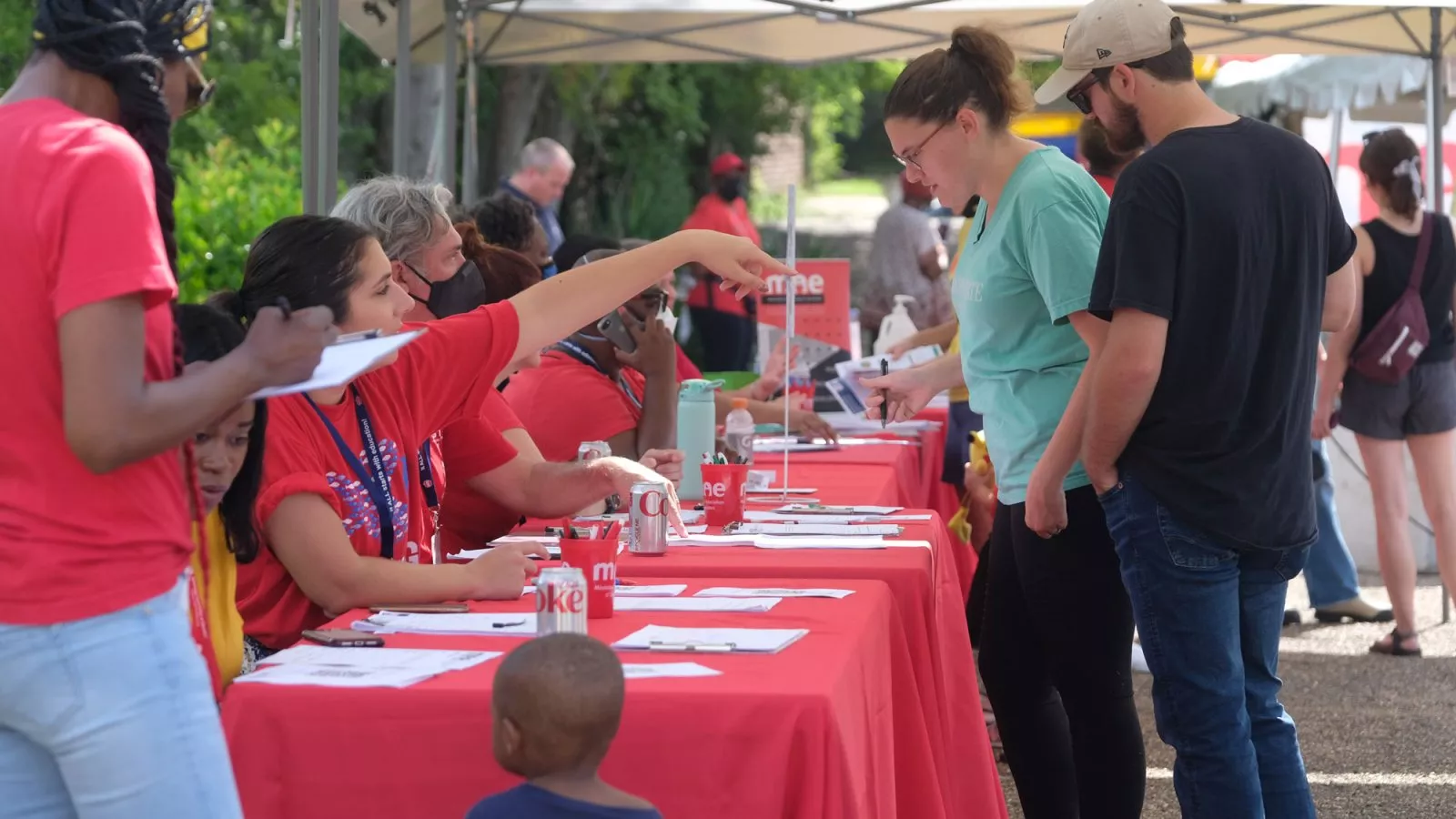 Educators sit at a table outside, helping with a voter registration campaign