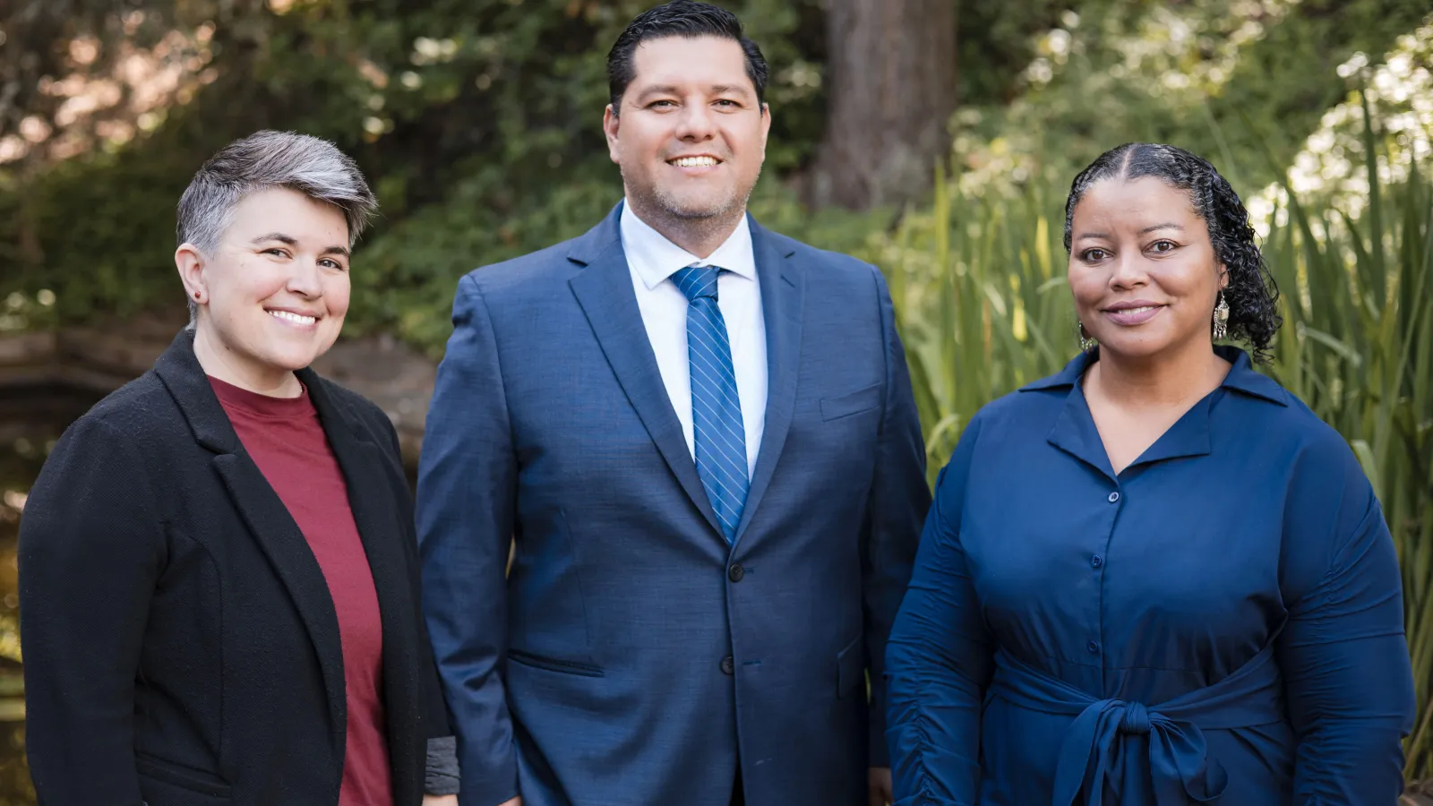 OEA executive team, including president, vice president, and equity director stand together in front of foliage.