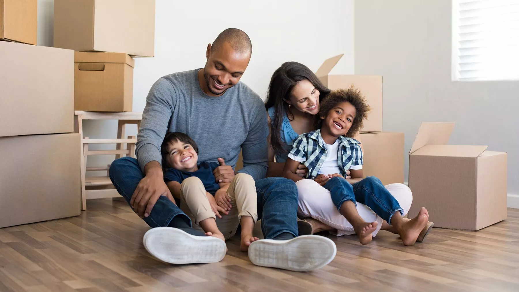 A family sits in front of moving boxes.