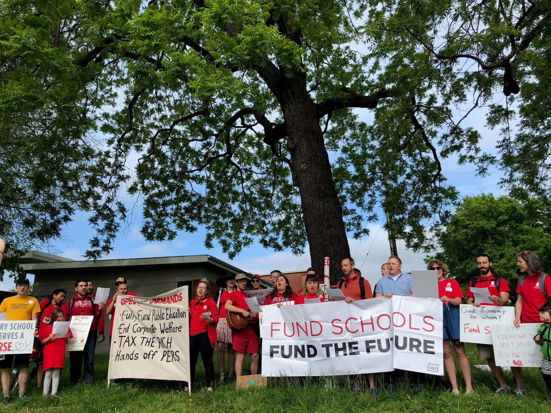 Students and educators hold up rally signs advocating for increased funding for public education