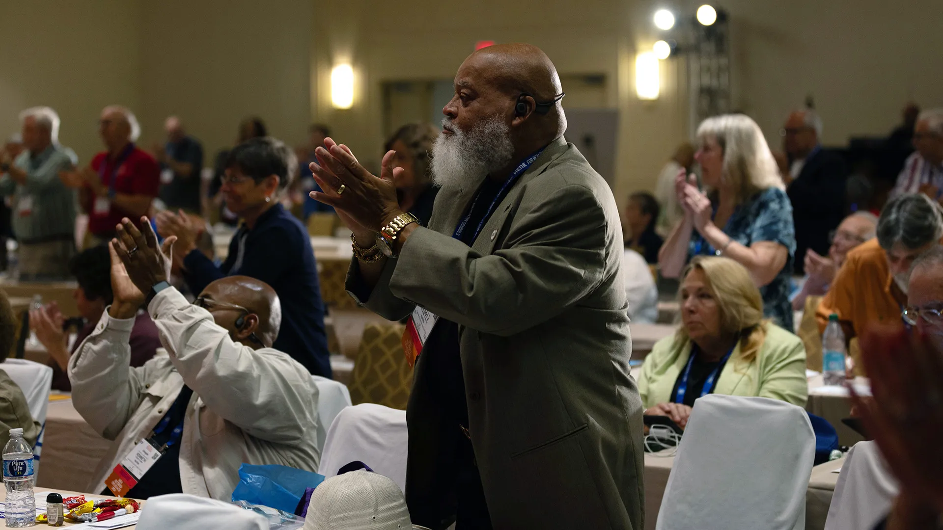 mad with beard standing and applauding in a conference meeting room