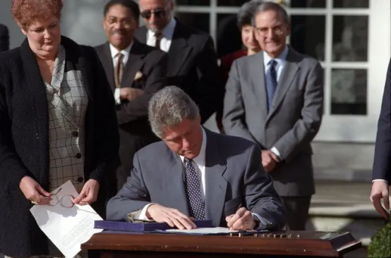 Photo of Bill Clinton signing legislation at desk