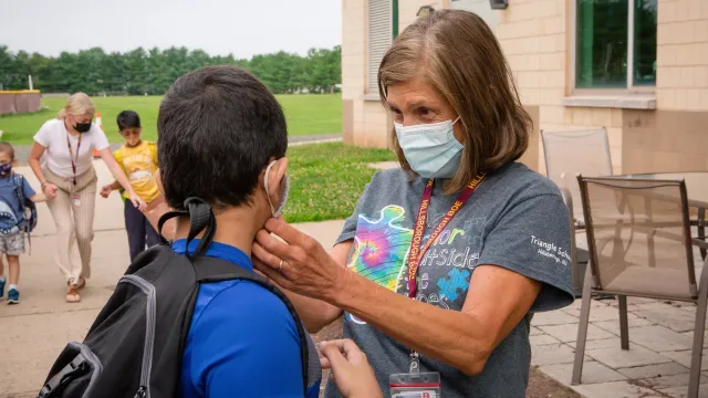 Member in mask comforts student