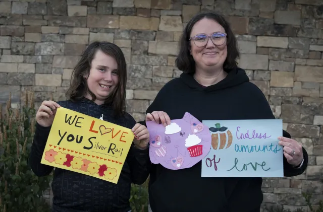 Child and adult hold signs supporting Silver Rail victims