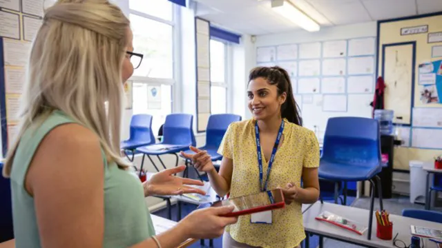 two teachers talking in an empty classroom