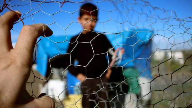 A child appears behind a fence