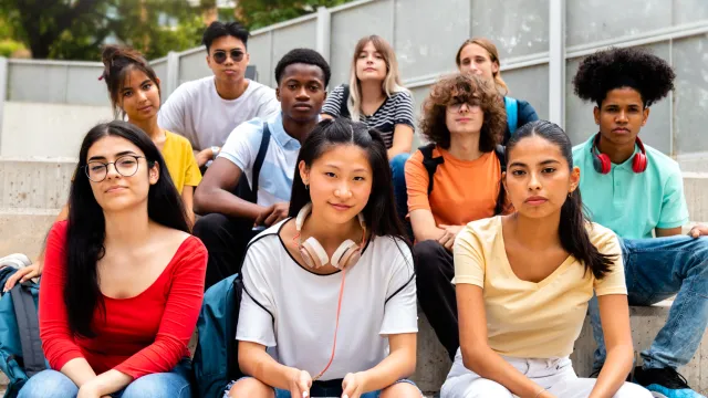 10 diverse high school students sit outside on a bench