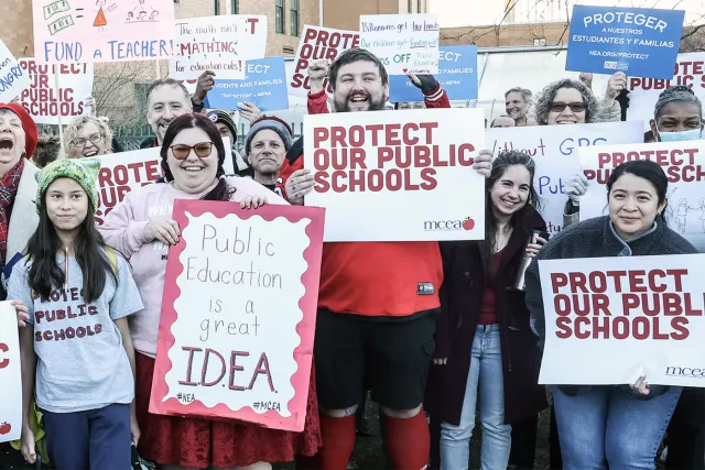 Protester hold up signs asking protect our public schools