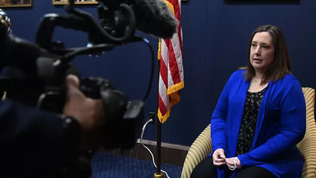 A woman in a blue jacket in front of a camera