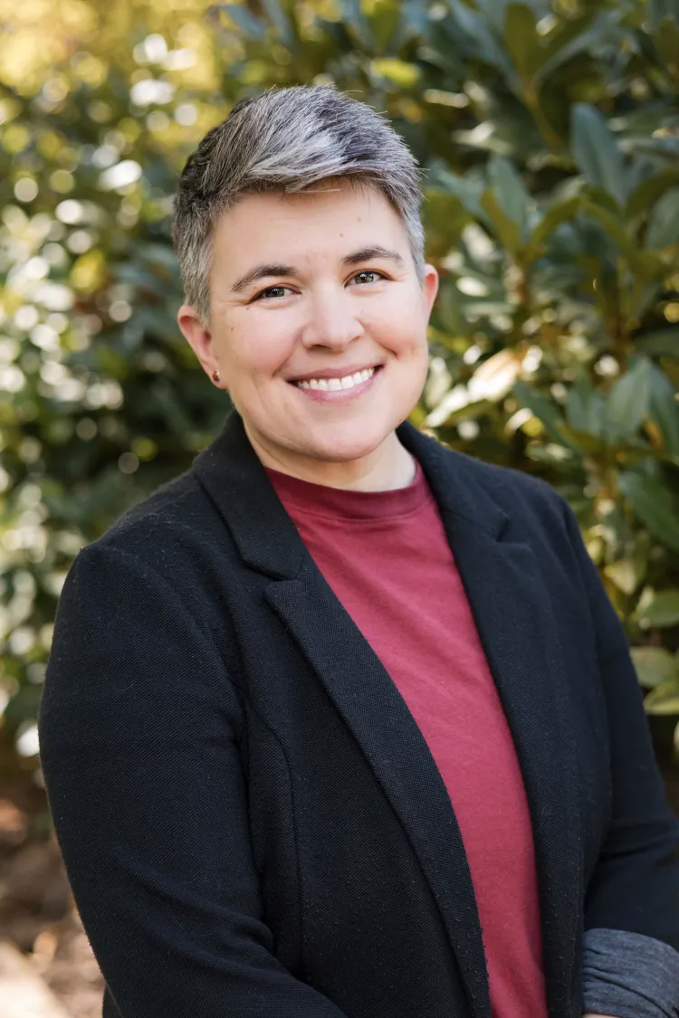 A headshot of OEA Vice President Lindsay Ray, standing in front of foliage